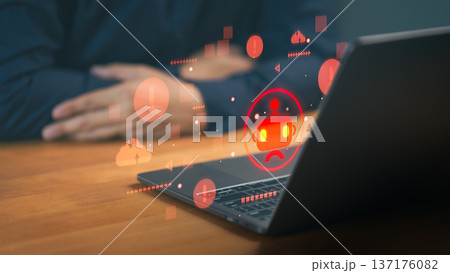 Cybersecurity concept of AI bot error or system failure. Red warning icons and sad robot hologram on laptop screen representing technical glitch, data breach, and malware attack. 137176082