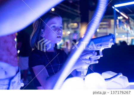Girl playing laser tag shooting game in neon lit Girl playing laser tag shooting game in neon lit 137176267