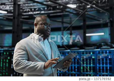 Computer scientist in data center runs system diagnostic tests on device, tracking resource utilization. Man in server hub scanning equipment, fixing network issues affecting rigs performance 137176592