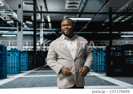 Smiling admin doing yearly checkup to prolong data center electronics life span and avoid downtime. Happy employee in server room monitoring server infrastructure components Smiling admin doing yearly checkup to prolong data center electronics life span and avoid downtime. Happy employee in server room monitoring server infrastructure components 137176608