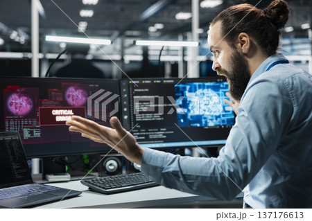 Angry data center engineer raging, struggling to fix malfunctions while using AI tools. Annoyed server hub worker upset by critical error while using artificial intelligence to optimize system health 137176613