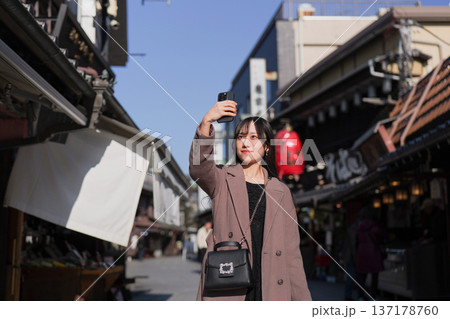 柴又の観光地をスマートフォンで撮影する若い女性 137178760