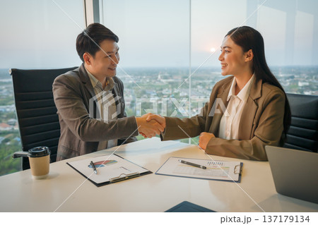 two professional businessman and businesswoman shaking hands after successful meeting in business office two professional businessman and businesswoman shaking hands after successful meeting in business office 137179134
