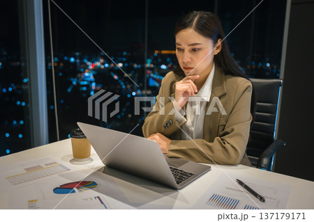 stressed businesswoman thinking while working on laptop computer in business office at night stressed businesswoman thinking while working on laptop computer in business office at night 137179171