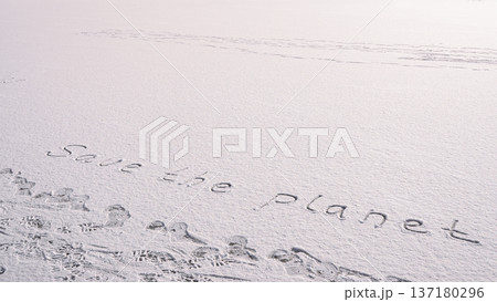 Written SAVE THE PLANET on snow background message ice outdoor on ground in winter. Writing text sign drawing on field in frozen background. Weather changing cold season has arrived environment Written SAVE THE PLANET on snow background message ice outdoor on ground in winter. Writing text sign drawing on field in frozen background. Weather changing cold season has arrived environment 137180296
