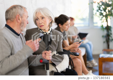 Elderly woman talking to senior man in clinic waiting area 137180381