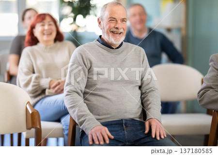 Portrait of a laughing elderly man at lecture among other elderly people Portrait of a laughing elderly man at lecture among other elderly people 137180585