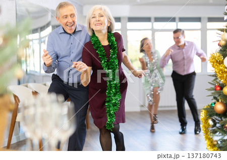 Group of adult active people dancing twist or rock and roll dance in dance hall during celebration Christmas and New Year Group of adult active people dancing twist or rock and roll dance in dance hall during celebration Christmas and New Year 137180743