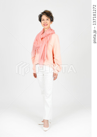 白バックで左足を前にモデル立ちをする50代女性 137181272