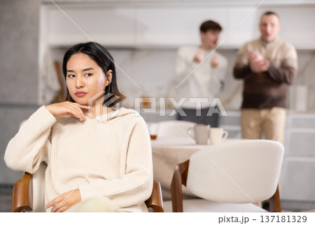 Upset woman not talking after disagreement with father and husband standing behind Upset woman not talking after disagreement with father and husband standing behind 137181329