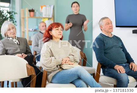 Elderly people watching presentation while young girl stands in background Elderly people watching presentation while young girl stands in background 137181330