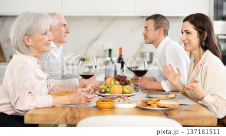Mother-in-law and daughter-in-law chatting friendly at family dinner Mother-in-law and daughter-in-law chatting friendly at family dinner 137181511