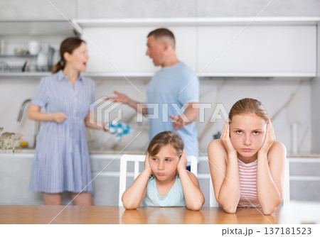Distraught teenage girls suffering from parents conflict sitting in kitchen 137181523