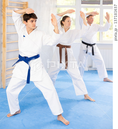 Group of people in kimonos try new fighting techniques at karate lessons Group of people in kimonos try new fighting techniques at karate lessons 137181637