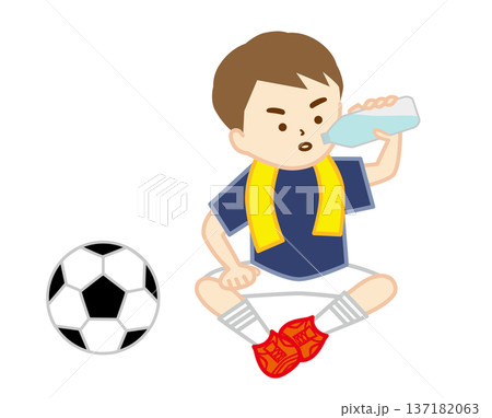 首にタオルを巻いて地面に座って水分補給をするサッカー少年 137182063