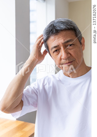 窓辺で頭を抱えるシニア男性 137182076