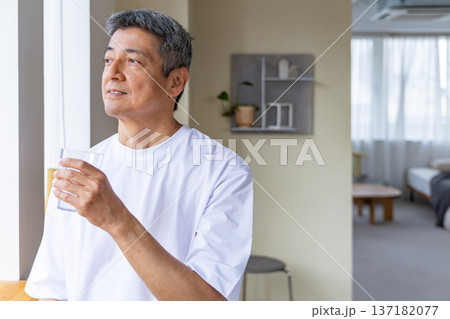 窓辺で水を飲むシニア男性 137182077