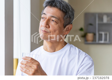 窓辺で水を飲むシニア男性 137182078