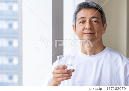 窓辺で水を飲むシニア男性 137182079
