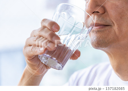 窓辺で水を飲むシニア男性 窓辺で水を飲むシニア男性 137182085