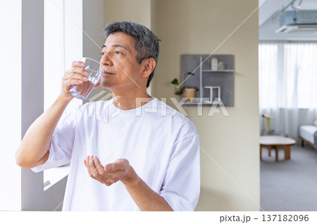 窓辺で薬を飲むシニア男性 137182096