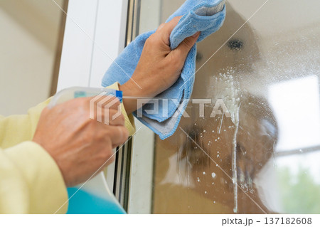 Close up, hand washing glass with glass cleaner and microfiber cloth. Cleaning and professional house cleaning, small business 137182608