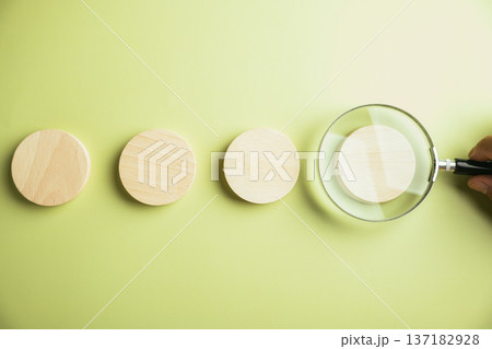 Magnifying glass over wooden circle on green background. Concept: search, focus, detail. Magnifying glass over wooden circle on green background. Concept: search, focus, detail. 137182928