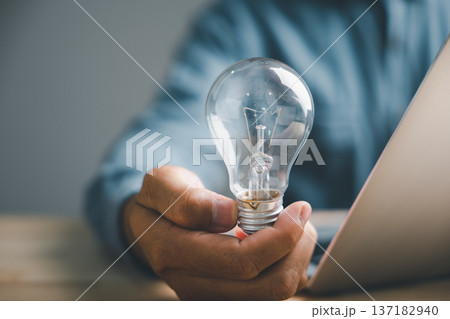 Sign of a great idea, a closeup man hand pose and gesture with a light bulb is a good sign for innovation, creativity, and developing new successful business solutions Sign of a great idea, a closeup man hand pose and gesture with a light bulb is a good sign for innovation, creativity, and developing new successful business solutions 137182940