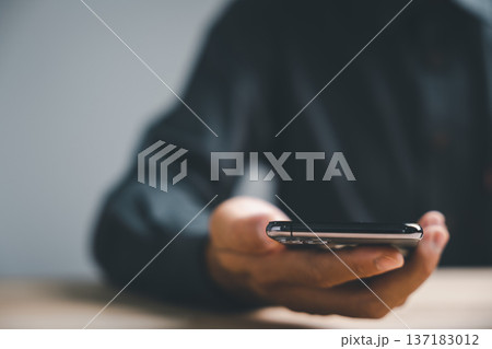 Close-up of a hand holding a smartphone with a blurred background. Close-up of a hand holding a smartphone with a blurred background. 137183012