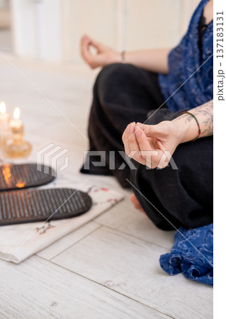 Sadhu board. Yoga tool. Woman sitting in lotus position mudra hands before sharp nails for practice meditation foot massage spiritual growth. 137183131
