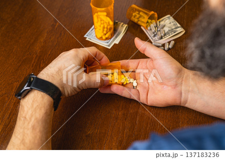 Person handling prescription pills and money on wooden table 137183236