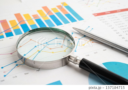 Magnifying glass on spreadsheet and graph paper. Financial data economy, Business. Magnifying glass on spreadsheet and graph paper. Financial data economy, Business. 137184715