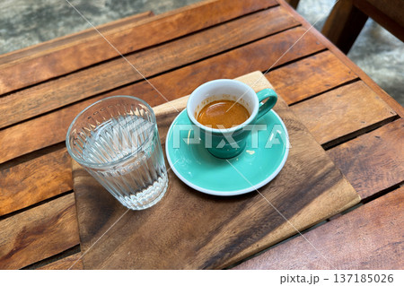 Beautiful unicorn latte art and a shot of espresso served on a wooden tray in a cafe. 137185026
