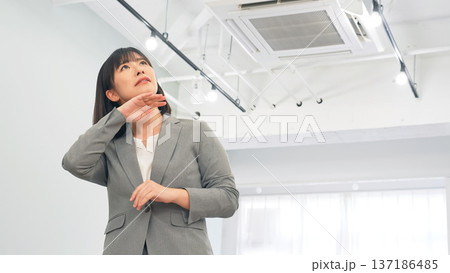 オフィスで汗をかく女性ビジネスパーソン オフィスで汗をかく女性ビジネスパーソン 137186485