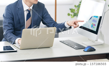 オフィスでPCを見ながら仕事する男性ビジネスパーソン 137186503