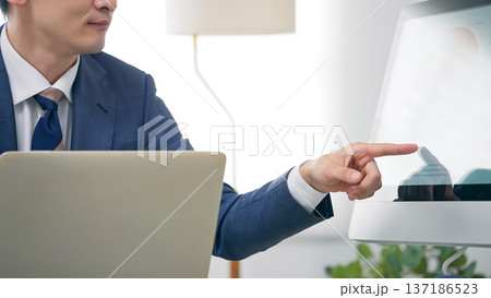 オフィスでPCを見ながら仕事する男性ビジネスパーソン オフィスでPCを見ながら仕事する男性ビジネスパーソン 137186523