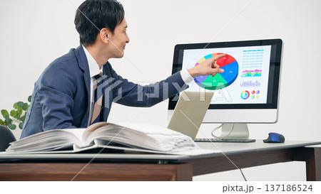 オフィスでPCを見ながら仕事する男性ビジネスパーソン 137186524