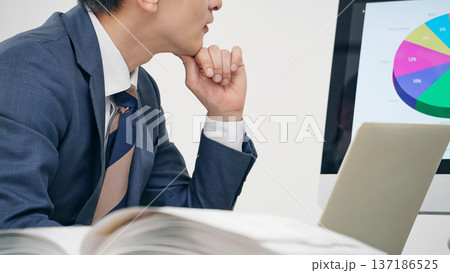 オフィスでPCを見ながら仕事する男性ビジネスパーソン 137186525