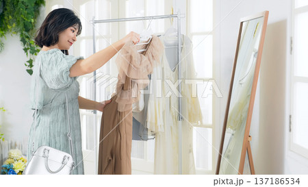 アパレルショップで鏡を見ながら洋服を選ぶ女性 アパレルショップで鏡を見ながら洋服を選ぶ女性 137186534