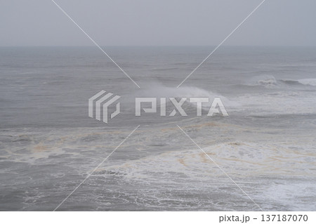 Cinematic shot of a massive wave cresting and breaking in the middle of a dark stormy ocean with white foam Cinematic shot of a massive wave cresting and breaking in the middle of a dark stormy ocean with white foam 137187070