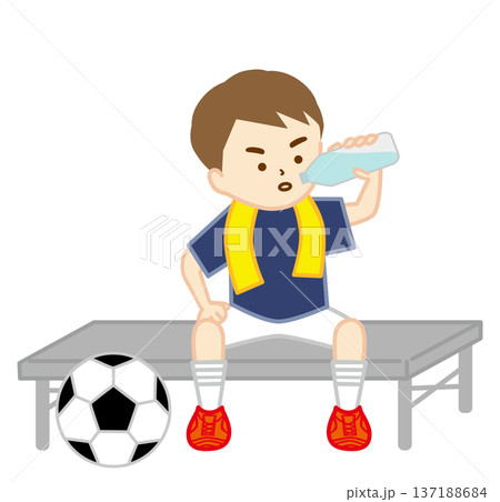 首にタオルを巻いてベンチに座って水分補給をするサッカー少年 137188684