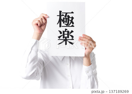 極楽と書かれた紙を持つ白いシャツを着た人物 137189269