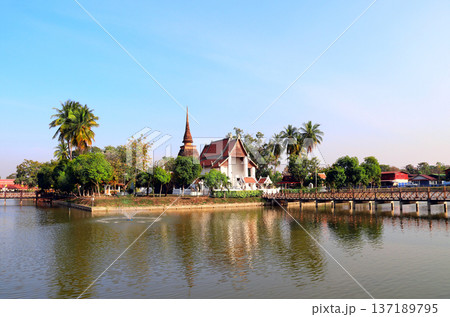 Bridge leading to Buddhist temple Saphan Boon Wat Traphang Thong on island, Sukhothai, Thailand. Picturesque landscape with temple in middle of lake, Sukhothai. Topic of vacation, travel, trip, cruise 137189795