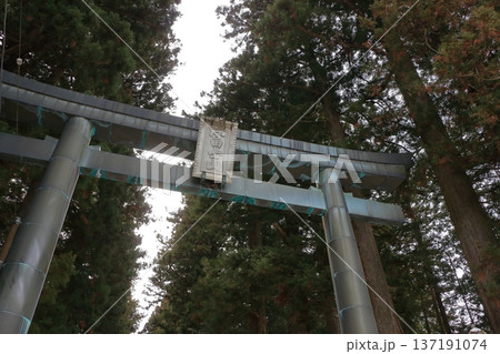 The gates to the Kitaguchi Hongu Sengen Jinja shrine, the entrance to the path to climb Mt. Fuji, lined with stone lanterns in Fujiyoshida in Yamanashi Japan on a snow covered winter day. 137191074