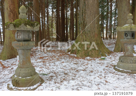 The long pathway to the Kitaguchi Hongu Sengen Jinja shrine, the entrance to the path to climb Mt. Fuji, lined with stone lanterns in Fujiyoshida in Yamanashi Japan on a snow covered winter day. The long pathway to the Kitaguchi Hongu Sengen Jinja shrine, the entrance to the path to climb Mt. Fuji, lined with stone lanterns in Fujiyoshida in Yamanashi Japan on a snow covered winter day. 137191079
