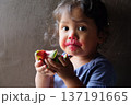Close-up of cute curly boy enjoying exotic dragon fruit with red smudged face 137191665