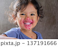 Close-up of cute curly boy enjoying exotic dragon fruit with red smudged face 137191666