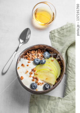 Natural greek yogurt with granola, blueberry and apple in a bowl on a light background with honey Natural greek yogurt with granola, blueberry and apple in a bowl on a light background with honey 137191760