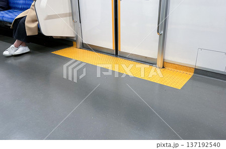 電車内の床とドア付近に設置されたバリアフリーのドア位置表示板 137192540