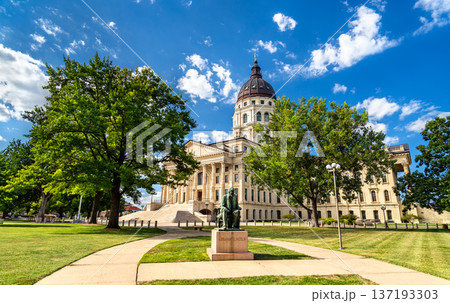 Scenic sunny view of the seated Abraham Lincoln statue on the lush green grounds of the historic Kansas State Capitol building in Topeka, United States 137193303